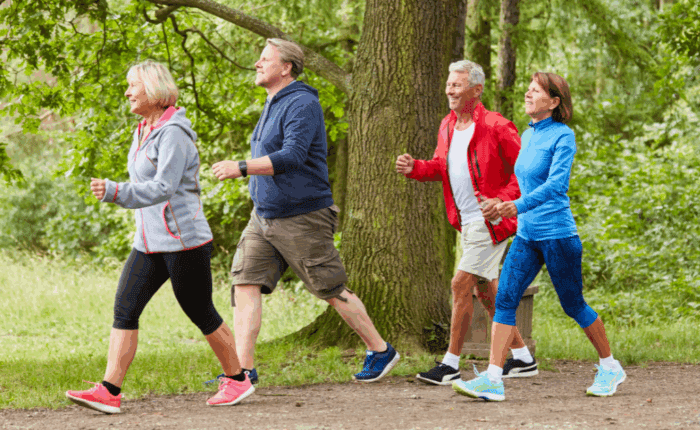 Four middle aged people walking in the woods with active wear on