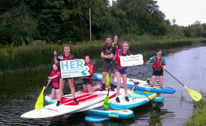Group of teenage girls and instructor on stand-up paddle boards on a river