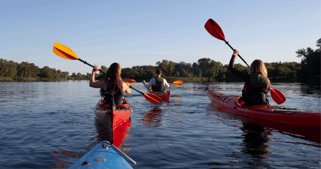 Two women and one man kayaking on a lake